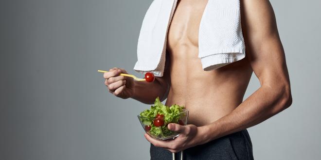 a young and muscular athlete eating a salad