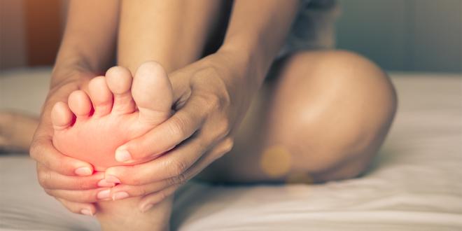 A woman massaging pain in her foot